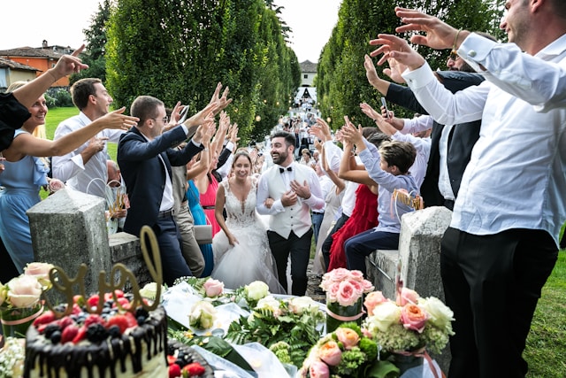 Novomanželé procházející svatebním špalírem tvořeným svatebními hosty s rukama nad hlavami. Zdroj: usplash.com