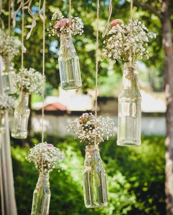 Svatební dekorace - kytice v lahvích zavěšených na větvích stromě