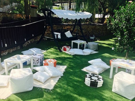 Svatební dekorace - bílé relaxační polštáře a deky na zelené trávě na svatební párty