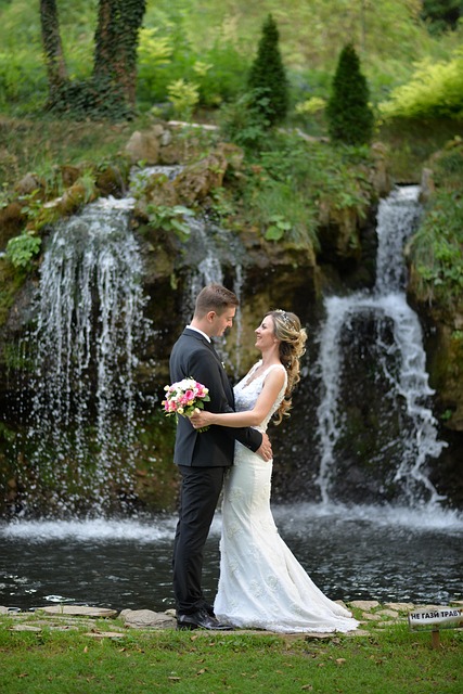 Novomanželé v objetí na zelené louce u vodopádu